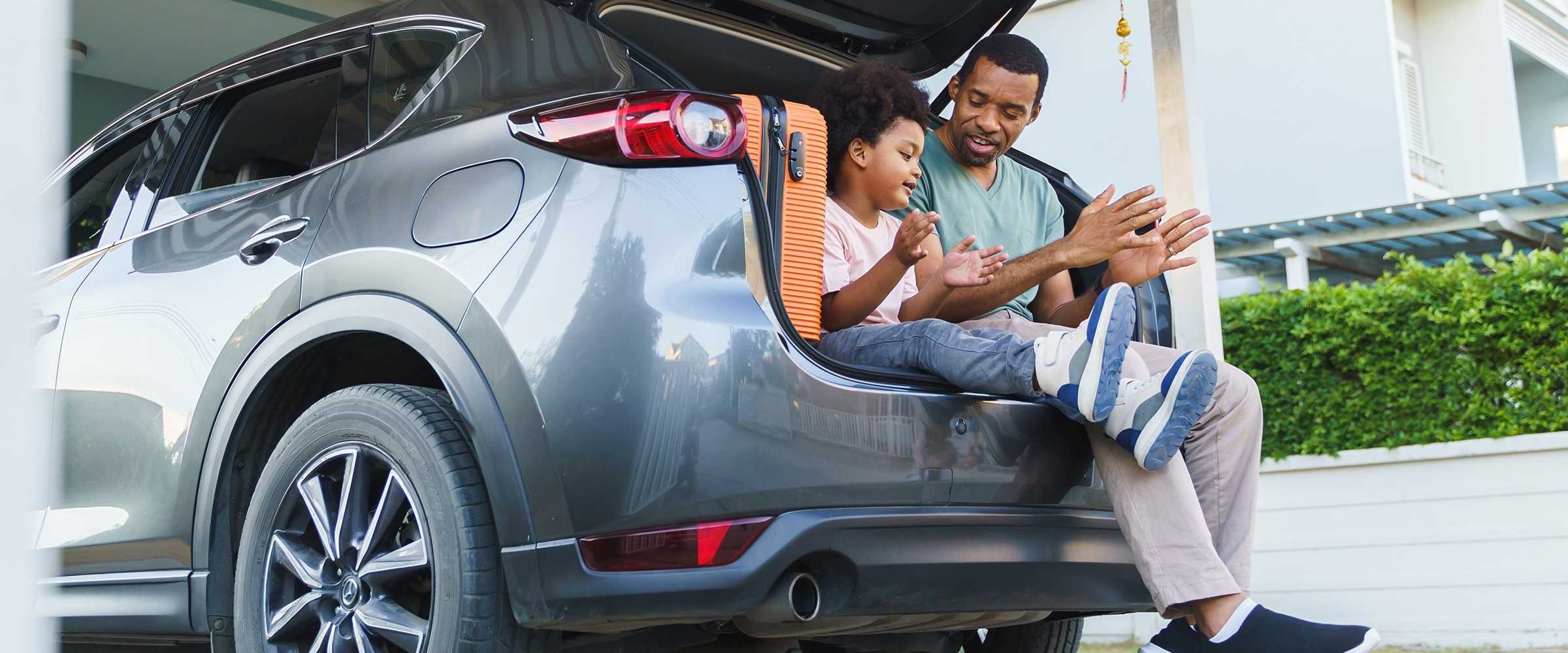 Father and daughter sitting in trunk